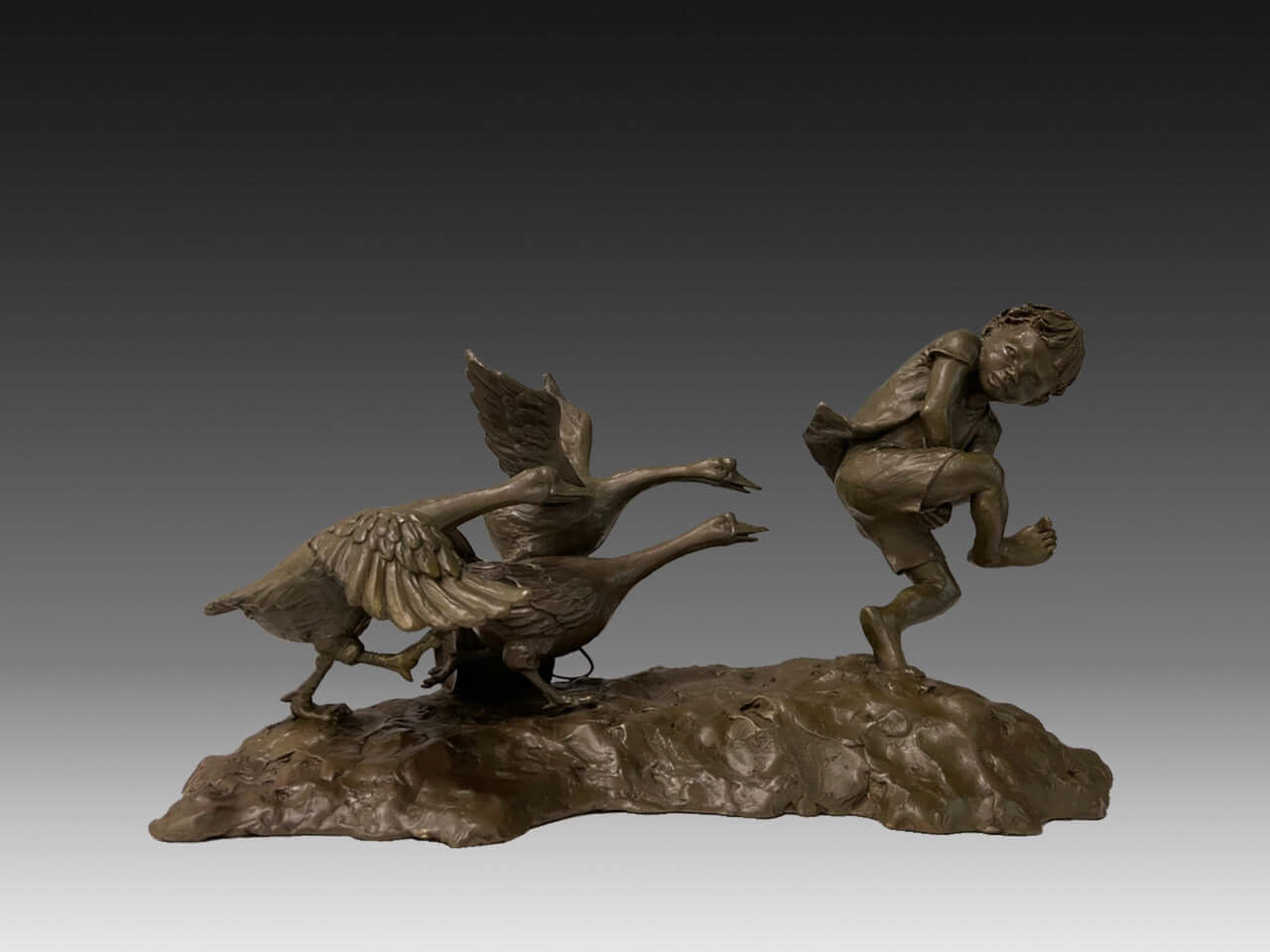 Child chased by domestic geese in a humorous bronze sculpture, capturing a moment of surprise and folklore.